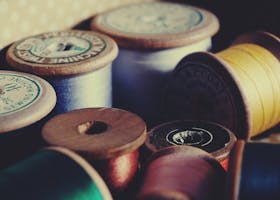 A close-up of vintage wooden spools displaying colorful sewing threads for crafting and tailoring.