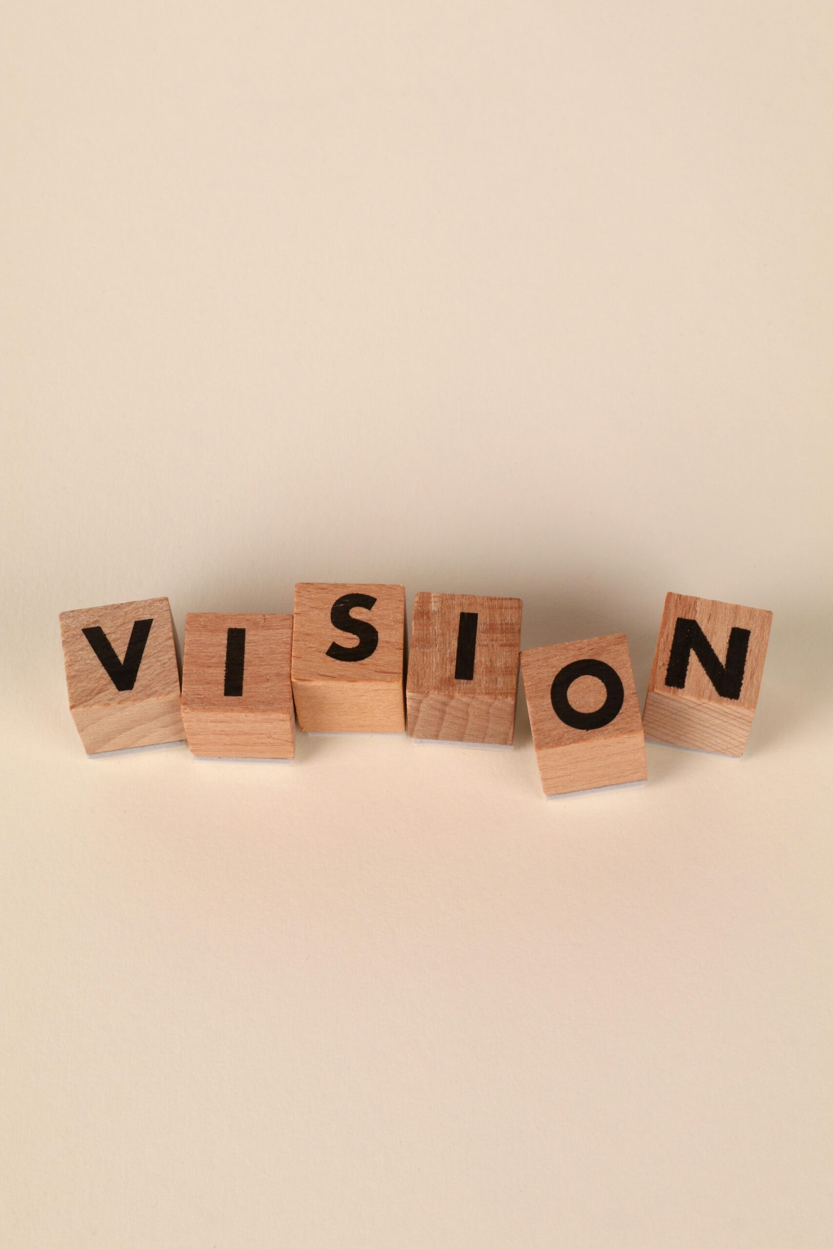 Wooden blocks spelling VISION on a beige background symbolizing clarity and foresight.