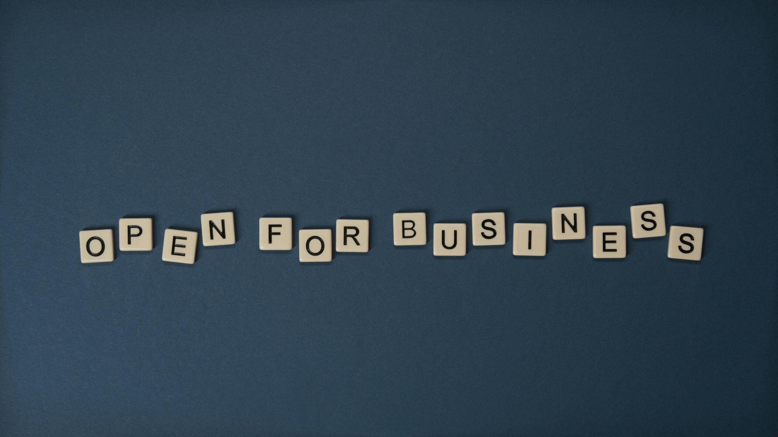 Creative flat lay with 'Open for Business' text on dark blue surface. Conceptual design ideal for business themes.